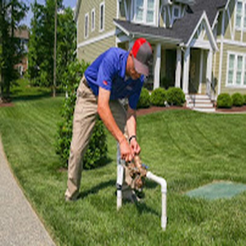 Technician servicing a backflow assembly in a front yard